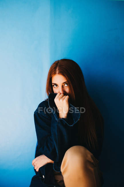 Приваблива жінка сидить біля синьої стіни — стокове фото