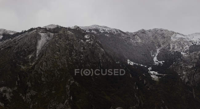Range of dark cold mountains with snow and haze — Stock Photo