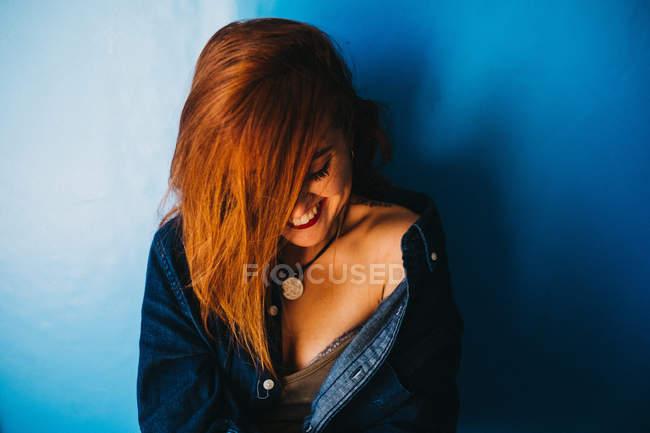 Mulher atraente de pé perto da parede azul — Fotografia de Stock
