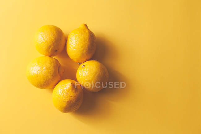 Limones frescos maduros sobre fondo amarillo - foto de stock