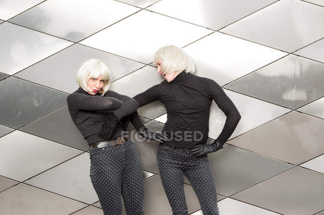 Blond lächelnde Damen in denselben Tüchern posieren an der Wand — Stockfoto