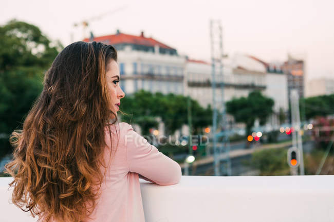Dreamy young looking away on footbridge above road with cars — Stock Photo