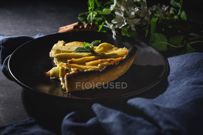 Apple pie with cinnamon and mint served on black plate — Stock Photo