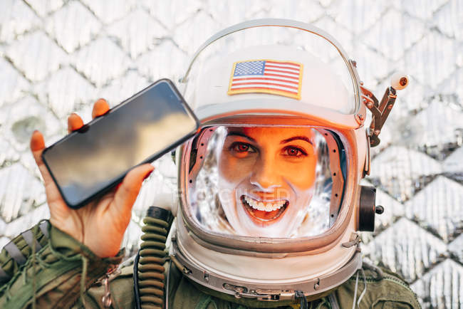 Female astronaut in illuminated vintage helmet with mobile phone — Stock Photo