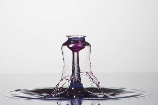 Éclaboussure de liquide transparent de couleur sur fond blanc — Photo de stock
