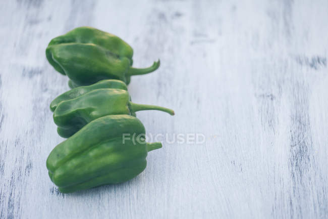 Pimentos verdes frescos na mesa de madeira branca — Fotografia de Stock