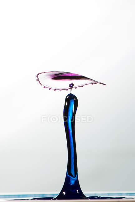 Closeup tiro de respingo de líquido transparente colorido no fundo branco — Fotografia de Stock