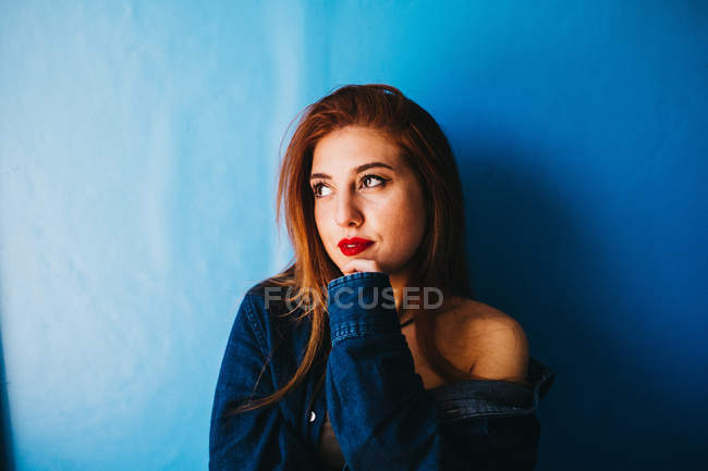 Mulher atraente de pé perto da parede azul — Fotografia de Stock