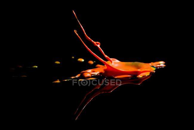 Closeup tiro de belo respingo de tinta laranja incrível no fundo preto — Fotografia de Stock