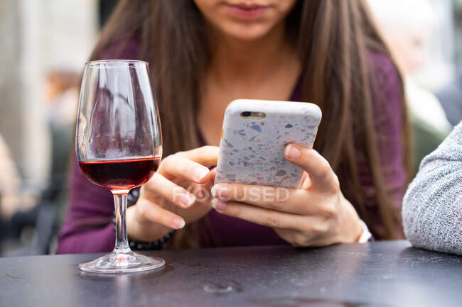 Mulher usando smartphone perto de copo de vinho — Fotografia de Stock