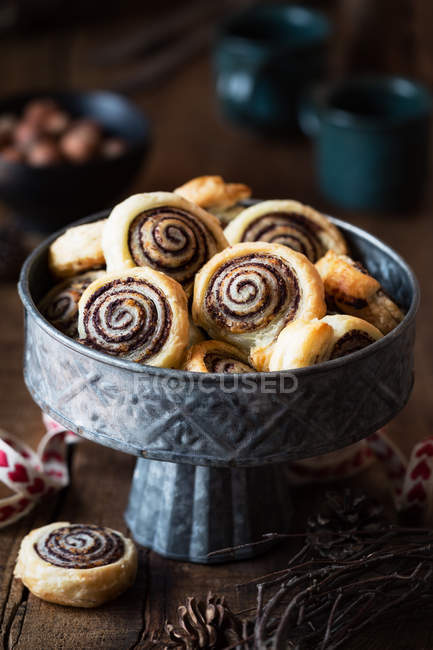 Puff pastry swirls filled with cinnamon in metal bowl on wooden tabletop. — Stock Photo