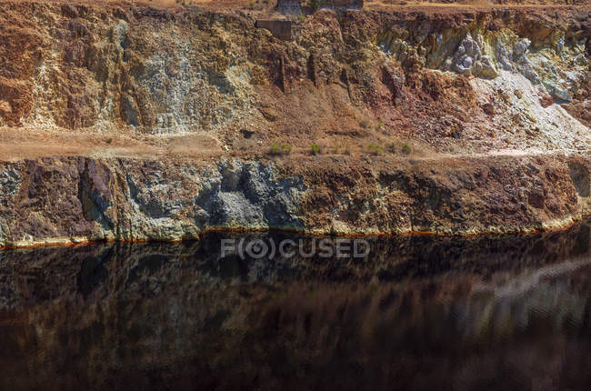 Superficie tranquila del agua cerca de la ladera de la cantera en la mina de Santo Domingos, Portugal - foto de stock