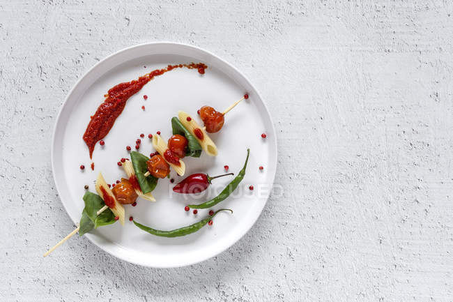 Macarrão com tomate e manjericão em pau na placa no fundo branco — Fotografia de Stock
