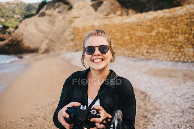 Young barefoot female using photo camera while standing on seashore in Altea, Spain — Stock Photo