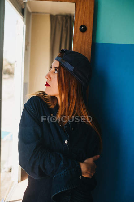 Mulher atraente em boné e camisa perto do espelho — Fotografia de Stock