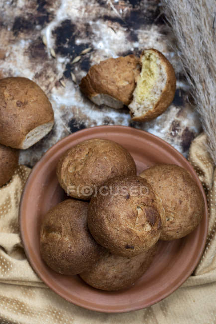 Panini appena sfornati su piatto marrone su sfondo rustico — Foto stock