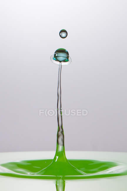Closeup tiro de respingo de líquido transparente de cor no fundo cinza — Fotografia de Stock