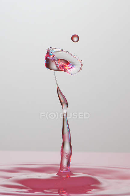 Closeup shot of splash of transparent liquid of color on gray background — Stock Photo