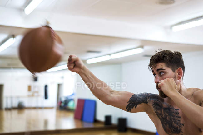 Jovem formação cara no ginásio com saco de soco — Fotografia de Stock