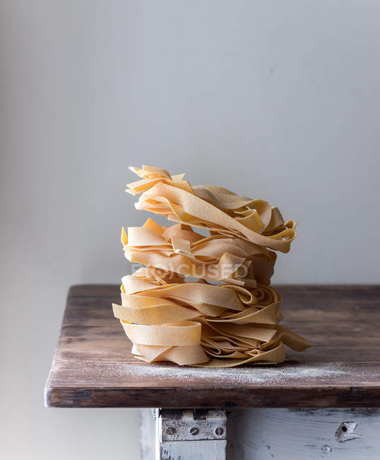 Pile di pappardelle spaghetti di grano su vecchio tavolo di legno su fondo grigio — Foto stock