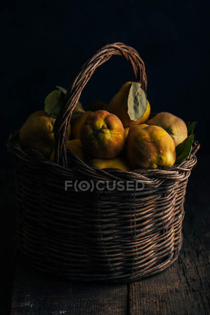 Frisch gepflückte Quitten im Korb auf dunklem Holzgrund — Stockfoto