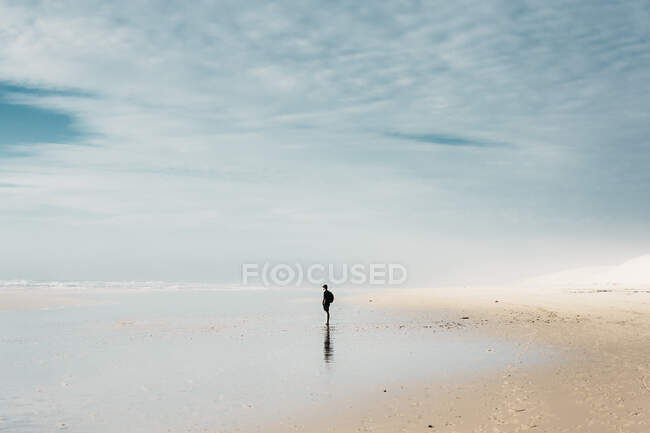 Seitenansicht Person mit Rucksack steht am Ufer in der Nähe von Wasser und schönen Himmel mit Wolken in Frankreich — Stockfoto