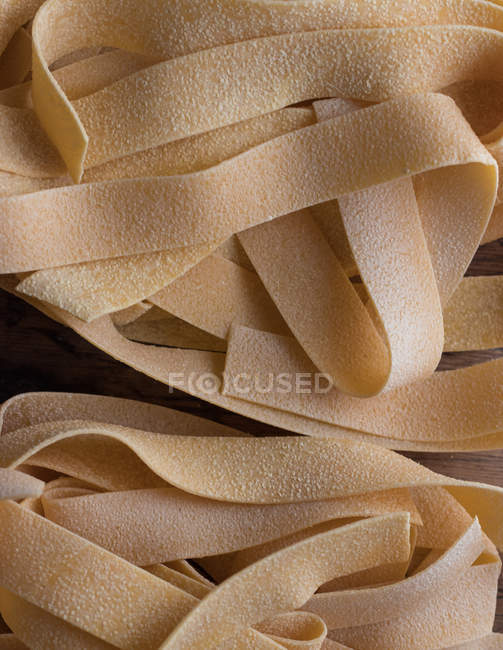 Haufen ungekochter Pappardelle Spaghetti auf Holztisch — Stockfoto