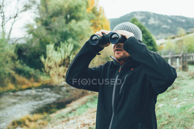 Un giovane caucasico con binocolo in montagna nei colori autunnali — Foto stock
