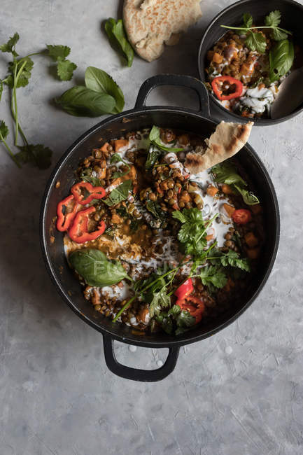 Pentola di ragù con lenticchia e curry di patate dolci e ciotola su tavolo grigio — Foto stock