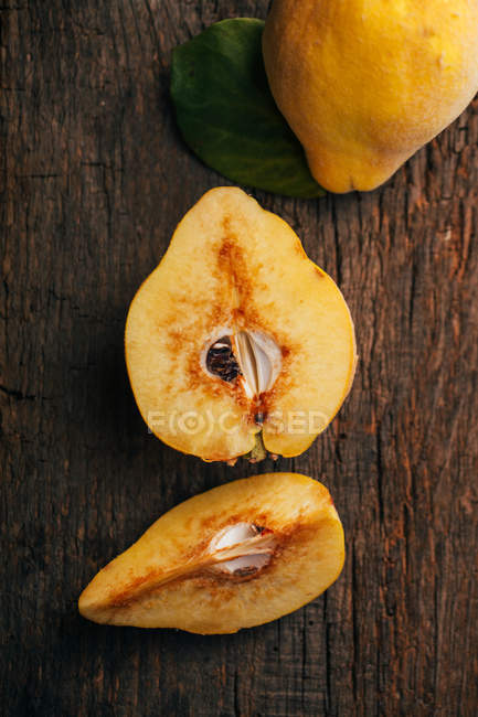 Marmelos inteiros e cortados pela metade no fundo de madeira escura — Fotografia de Stock