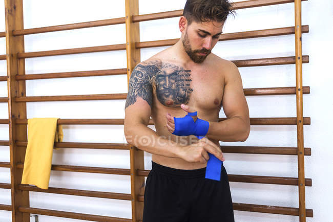 Jeune boxeur enveloppant les mains avant l'entraînement en salle de gym — Photo de stock