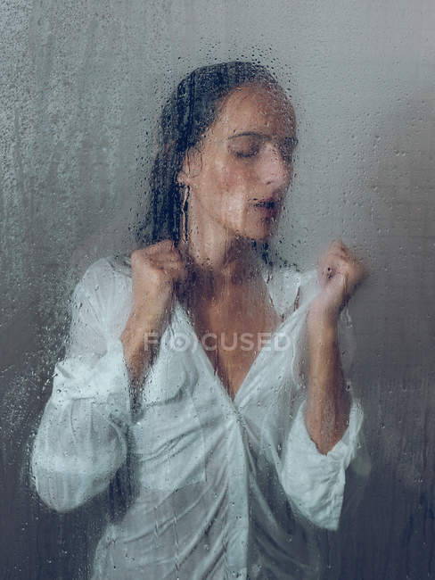 Esguichando mulher na camisa posando na cabine do chuveiro — Fotografia de Stock