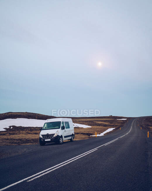 Білий фургон на сільській дорозі між дикими землями і сонцем на блакитному небі в Ісландії. — стокове фото