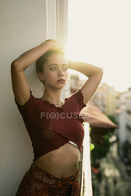 Affascinante giovane signora bruna in piedi sul balcone con le mani nei capelli — Foto stock