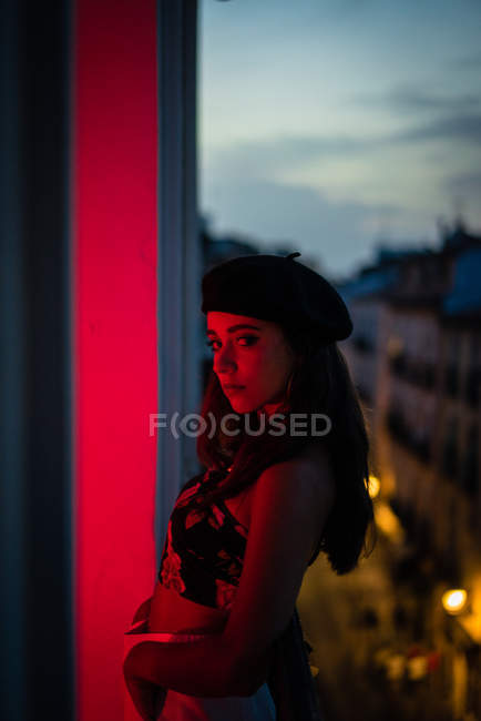 Charmante jeune femme en débardeur et béret debout sur le balcon en rougeur — Photo de stock