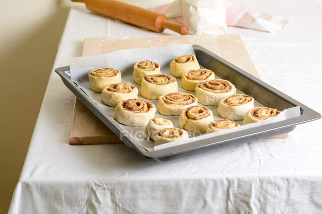 Bunch de petits pains non cuits sur la plaque de cuisson sur la table de cuisine . — Photo de stock