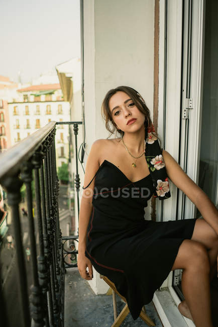 Retrato de encantadora jovem senhora no vestido sentado na varanda — Fotografia de Stock