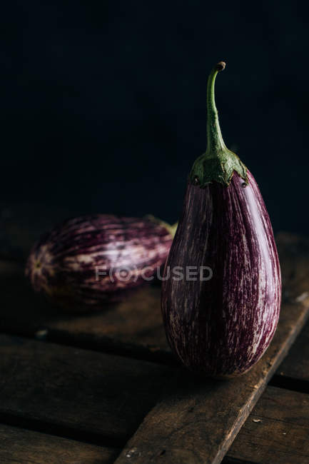 Fresh eggplants on wooden table on dark background — Stock Photo
