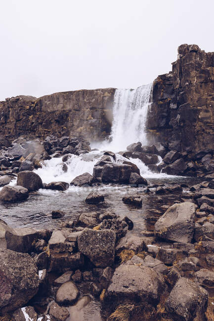 Cascada de agua cayendo en el río que fluye entre rocas en Islandia - foto de stock
