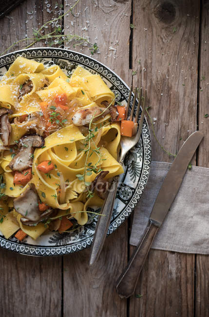 Тарелка приготовленных спагетти с тыквой и колбасой на деревянном столе — стоковое фото