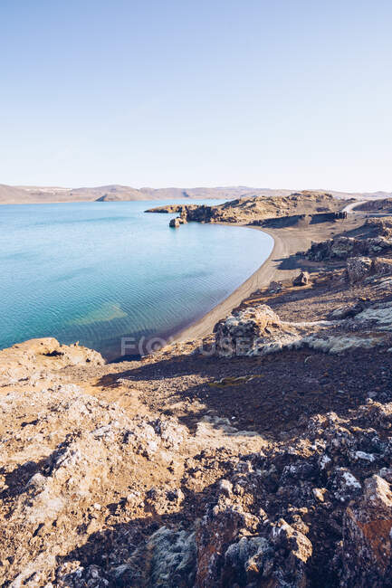 Stone shore of wide river with blue water between hills in Iceland — Stock Photo