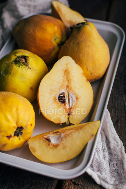 Fresh ripe quinces on tray on dark wooden background — Stock Photo