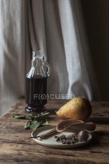 Fresh pear and spices on wooden table near bottle of red wine — Stock Photo