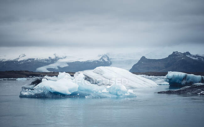 Paisaje de agua fría de mar con iceberg blanco contra el cielo nublado, Islandia - foto de stock