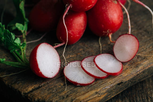 Fresh whole and sliced radishes on wooden background — Stock Photo