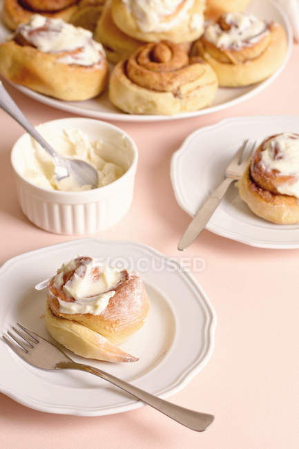Plates with yummy cinnamon buns with vanilla cream. — Stock Photo