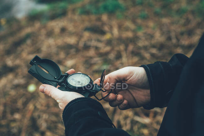Junger Mann mit Kompass im Berg neben einem Fluss mit braunem Hintergrund — Stockfoto