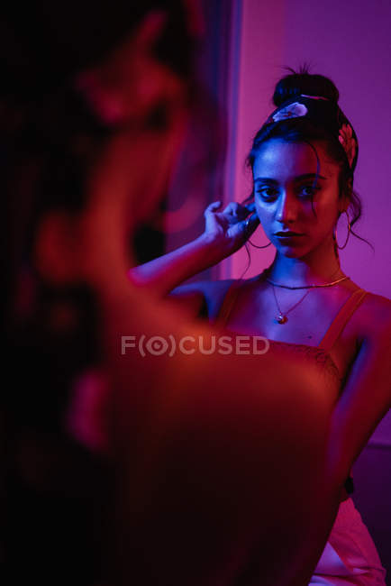 Reflection of charming young lady in mirror in redness — Stock Photo
