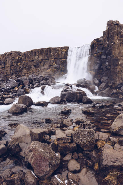 Каскад води, що падає в річці, що тече між скелями в Ісландії. — стокове фото