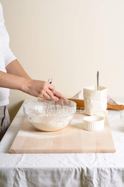Cropped of woman beating baking mix in bowl in kitchen. — Stock Photo